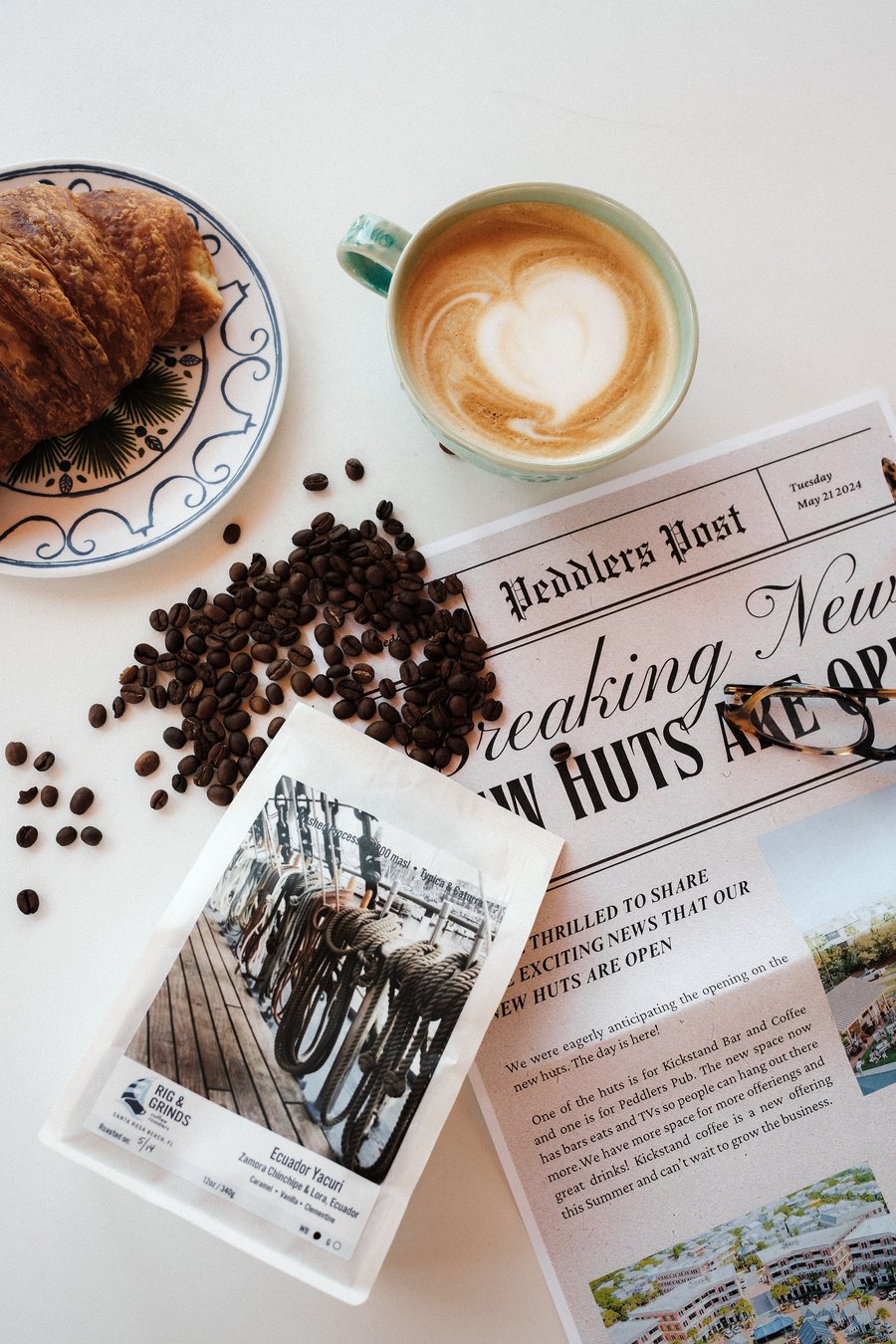 Latte with heart art next to a croissant and coffee beans