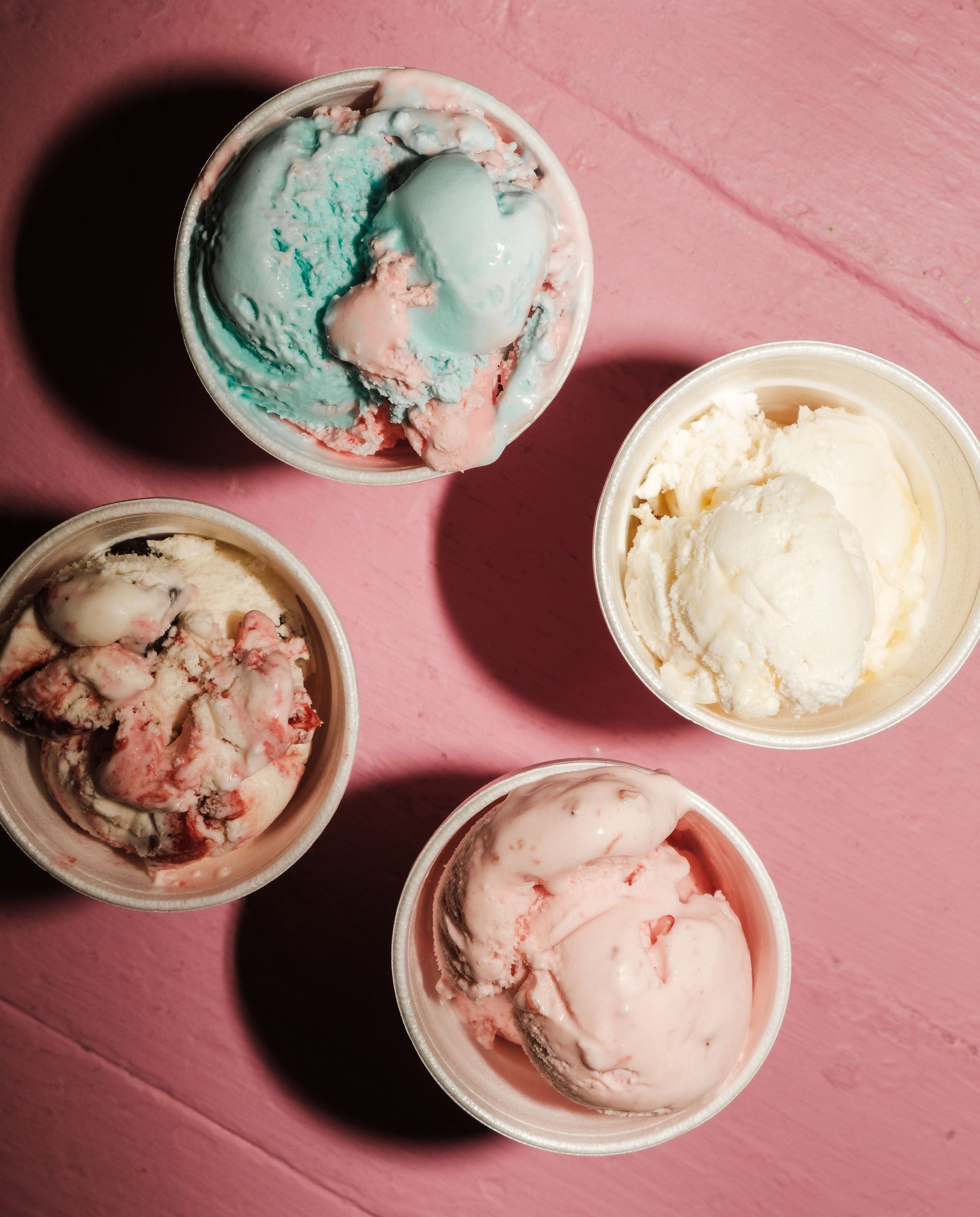 Cups of ice cream on a pink surface